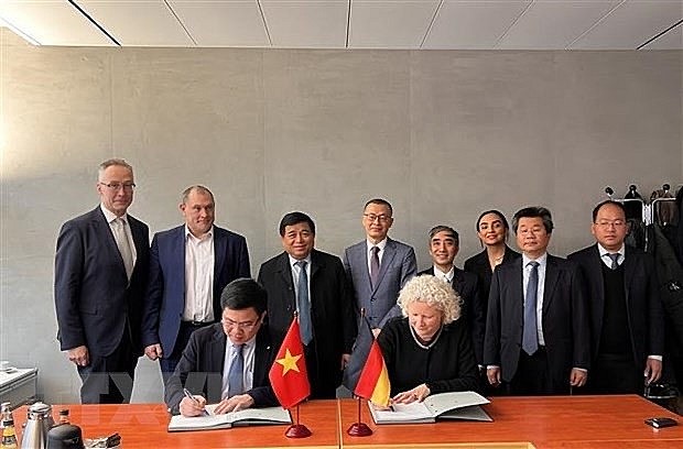 Le Manh Hung (L), head of the Vietnamese ministry' enterprise development department, and Alina Grumpert, Director of the German Agribusiness Alliance (GAA), signed a Memorandum of Understanding establishing a common cooperation framework under the witness of Minister Nguyen Chi Dung (standing, third, from left). (Photo: VNA)