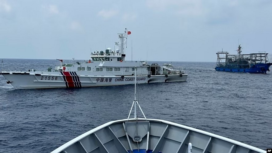 FILE - A Chinese coast guard ship, left, with a Chinese militia vessel, right, blocks Philippine coast guard ship BRP Sindangan as it tried to head towards Second Thomas Shoal at the disputed South China Sea during rotation and resupply mission on Oct. 4, 2023