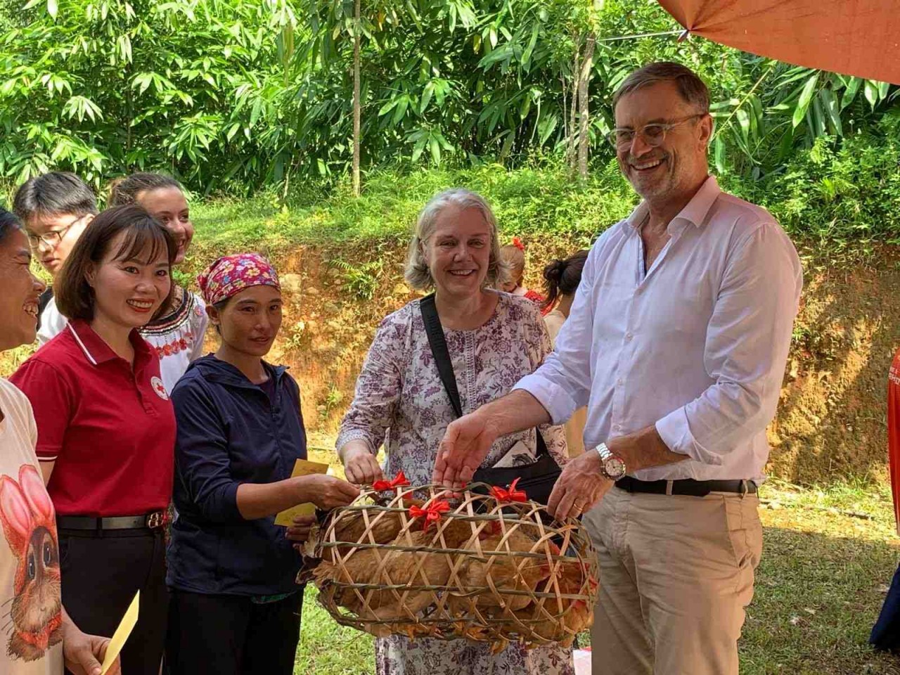 Florence Cavalier (second from right) and Olivier Brochet, French Ambassador to Vietnam (far right), present hens and sows to disadvantaged households in Ha Giang Province (now Tuyen Quang Province). (Photo: Provided by the family)
