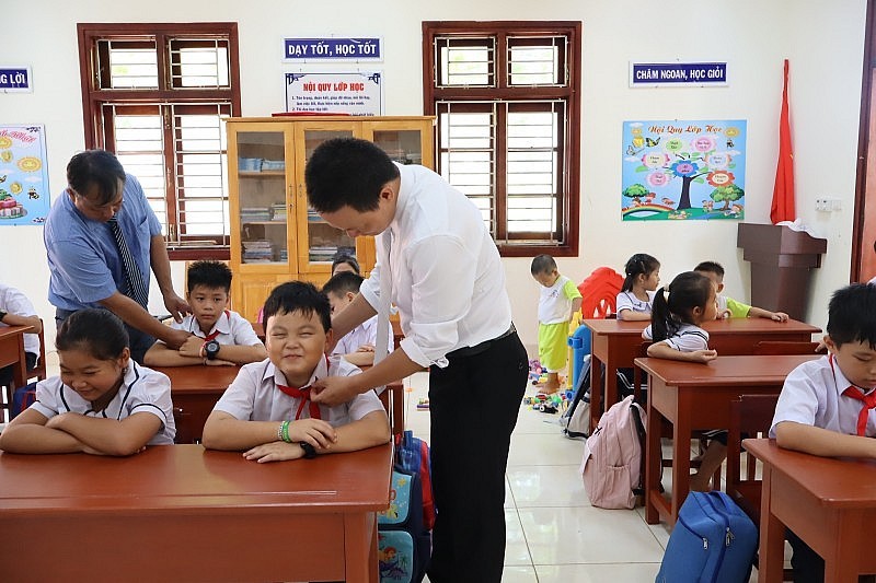 A teacher attentively cares for students during the opening ceremony. (Photo: Thanh Vu).