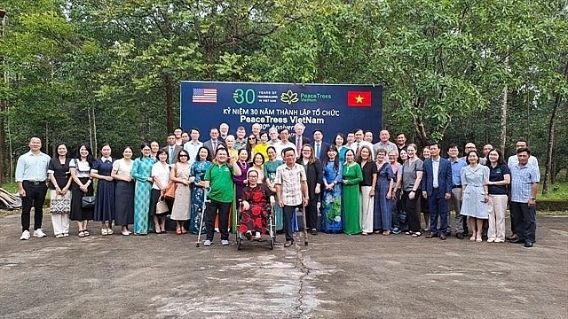 Friends of Vietnamese and the US join a group photo session in celebration of the 30th anniversary of PeaceTrees Vietnam (PTVN). (Photo: VNS)