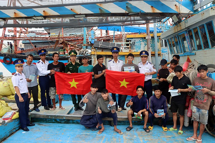 The Coast Guard distributes over 300 leaflets, presents 100 national flags, and gives 100 legal handbooks to local fishermen (Photo: Hong Van/baotintuc.vn) The Coast Guard distributes over 300 leaflets, presents 100 national flags, and gives 100 legal handbooks to local fishermen (Photo: Hong Van/baotintuc.vn)