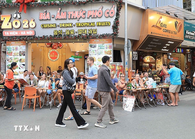 Foreign tourists savour local foods on Ta Hien street in Hanoi. (Photo: VNA)