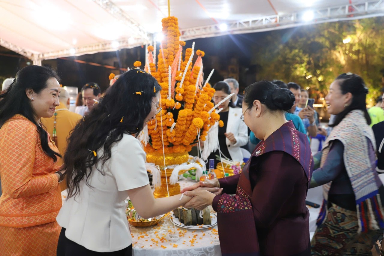 Delegates perform the wrist-tying ceremony. (Photo: Hanoi Moi Newspaper)