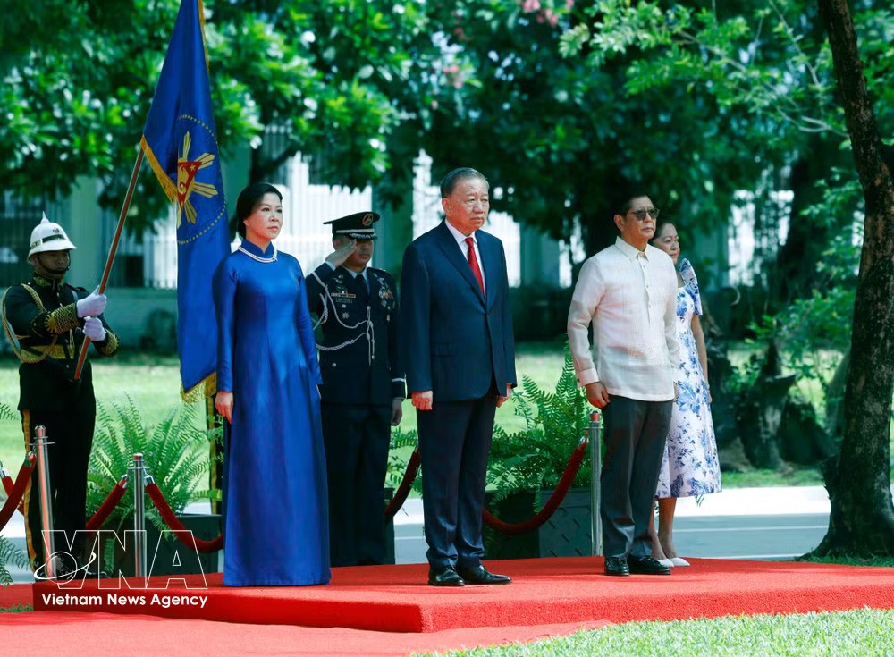 General Secretary of the Communist Party of Vietnam Central Committee and State President To Lam and his spouse, together with Philippine President Ferdinand Romualdez Marcos Jr. and his spouse, stand on the honour dais as military bands play the national anthems of Vietnam and the Philippines. (Photo: VNA)