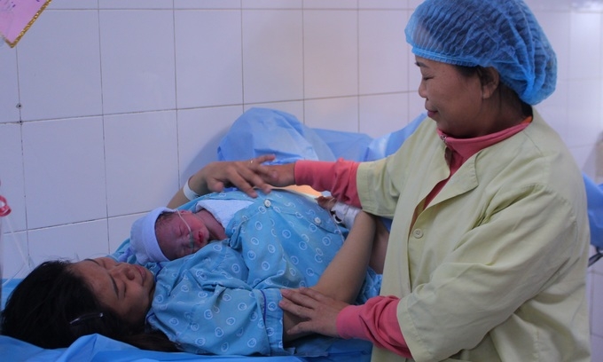 A family member helps a woman hold her new-born son at Tu Du Hospital in HCMC, January 2020.  