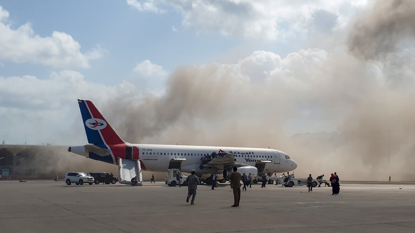 Smoke billows behind a plane that brought Yemen's new government to Aden International Airport on Wednesday. Explosions rocked the airport shortly after the plane arrived. (Photo: AFP)  