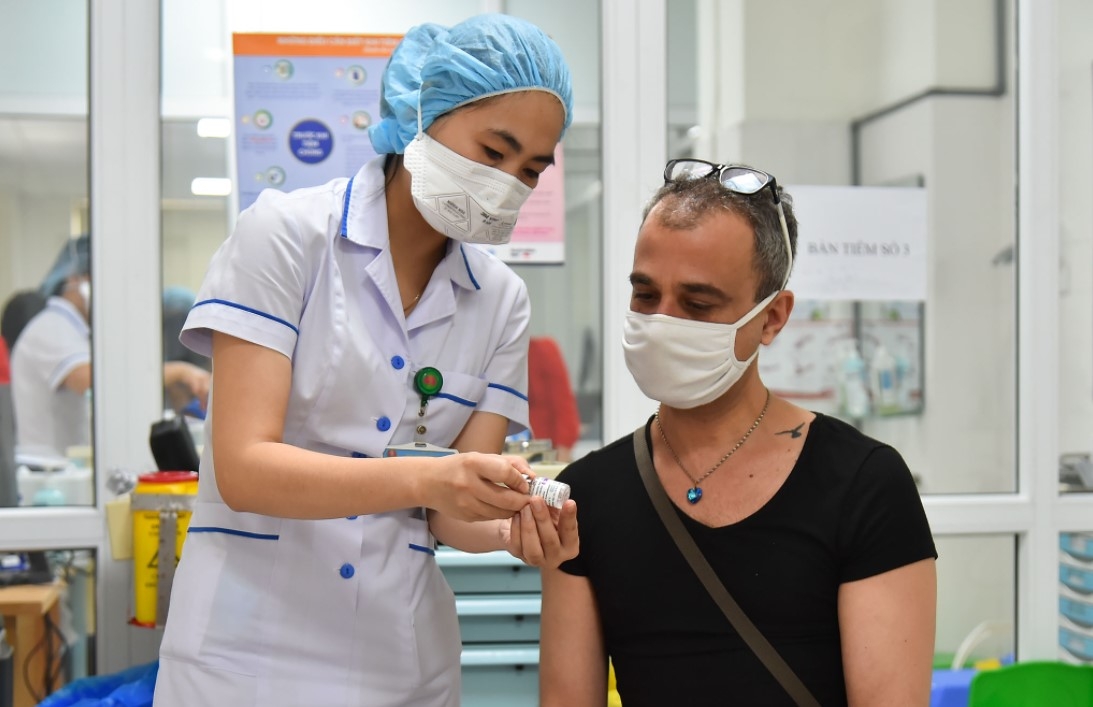 A medical worker explains pre-vaccination guidelines to a foreigner on June 10. Photo Bao Quoc Te