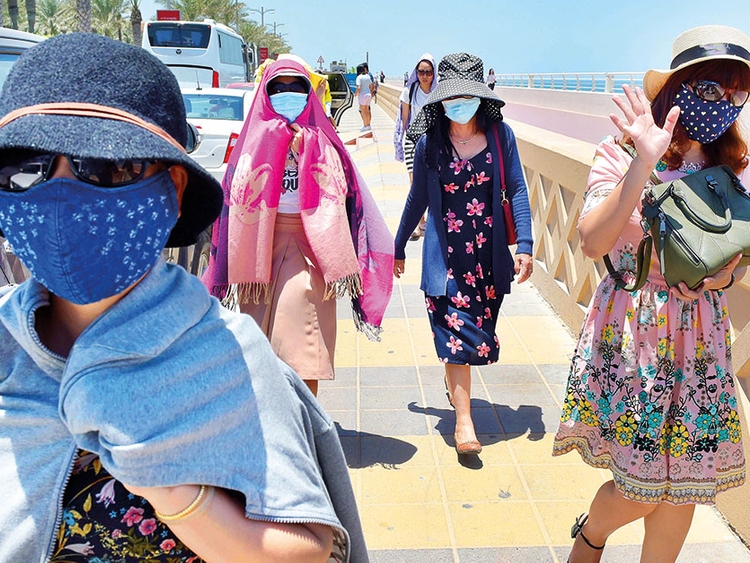 Tourists cover their faces to save themselves from the scorching sun in Dubai.