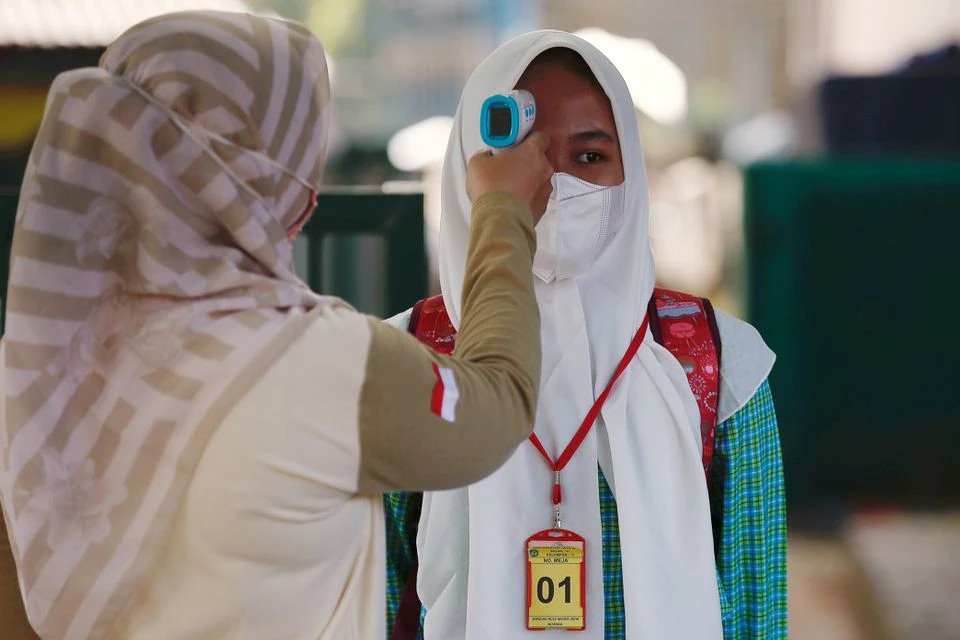An elementary school student wearing a face mask has her temperature checked before attending a classroom session, as schools reopen amid the coronavirus disease (COVID-19) pandemic in Bekasi, on the outskirts of Jakarta, March 24, 2021. REUTERS/Willy Kurniawan