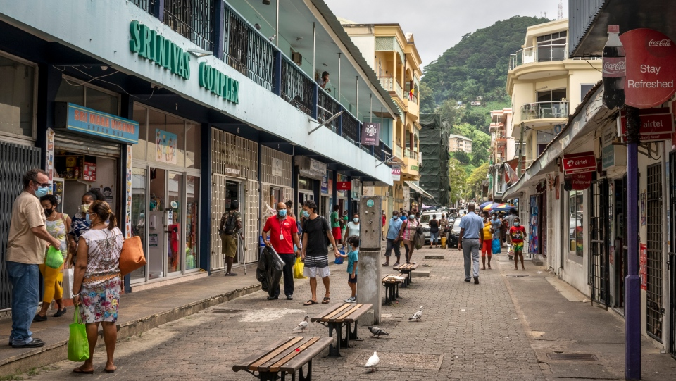 Pedestrians wear masks as they walk on a street in the capital Victoria, Mahe Island, Seychelles Thursday, Feb. 25, 2021. (AP Photo/Salim Ally)