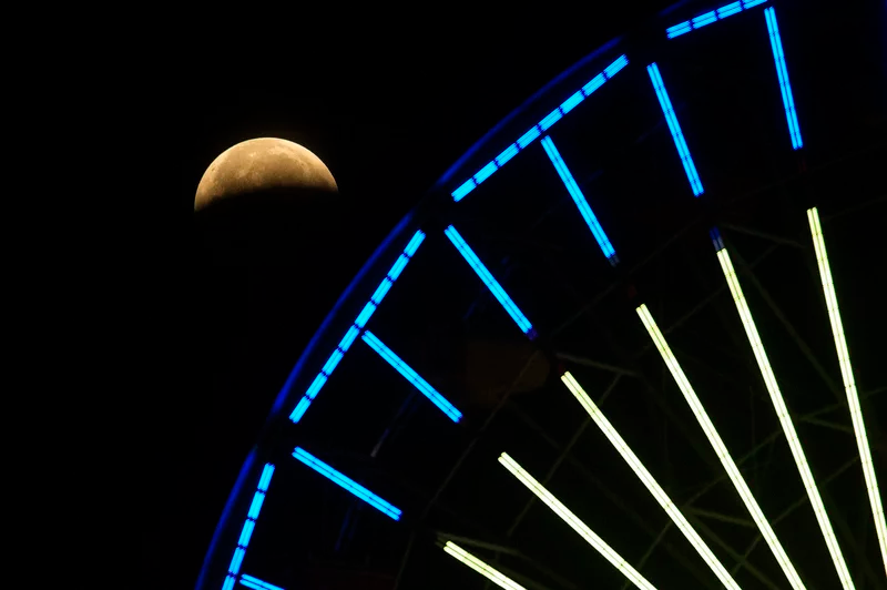 The lunar eclipse progresses behind a Ferris wheel over Santa Monica Beach on Wednesday in Santa Monica, Calif. The first total lunar eclipse in more than two years is coinciding with a supermoon. Ringo H.W. Chiu/AP