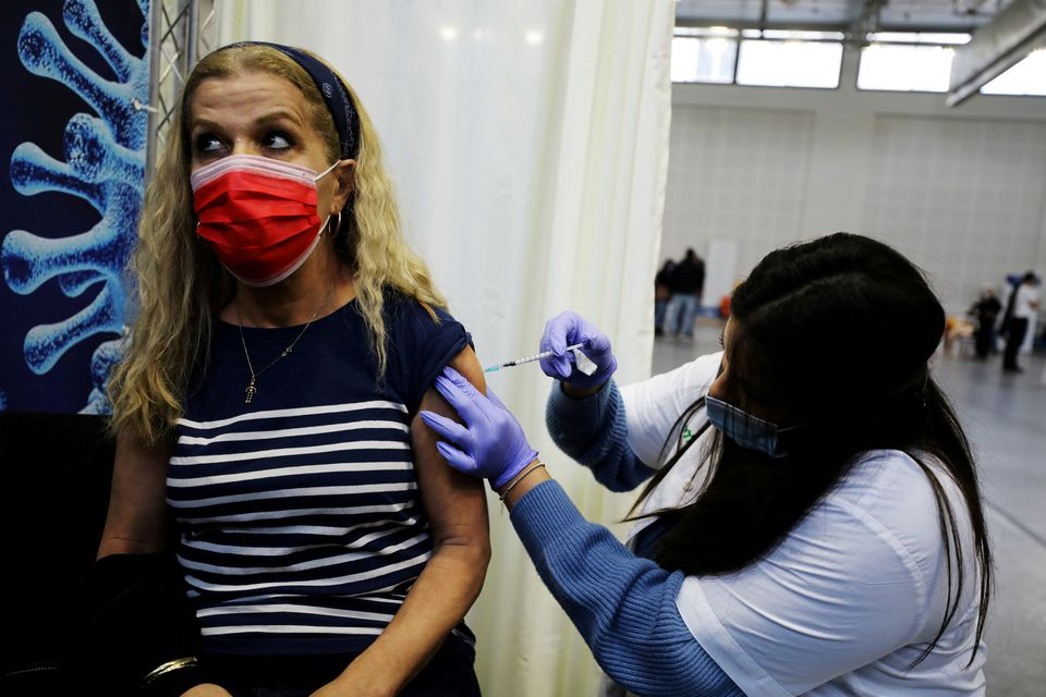  A woman receives a vaccination against the coronavirus disease (COVID-19) at a temporary Clalit healthcare maintenance organisation (HMO) centre, at a basketball court in Petah Tikva, Israel January 28, 2021. REUTERS/Ammar Awad