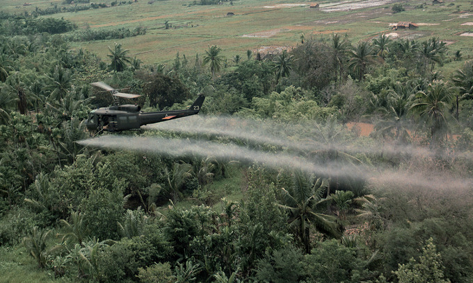 A U.S. helicopter sprays Agent Orange on a dense jungle area in the Mekong Delta during the Vietnam War. Photo by Shutterstock.