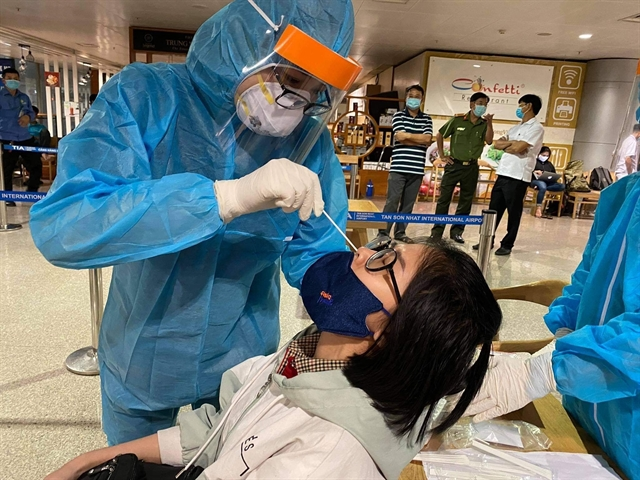 Health workers take samples for COVID-19 tests on an employee at Tân Sơn Nhất Airport on February 6. VNA/VNS Photo Đinh Hằng