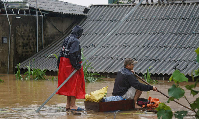 People in Ha Tinh Province travel on a raft as flood water has reached the roof of their houses, October 2020. Photo by VnExpress/Le Hoang.