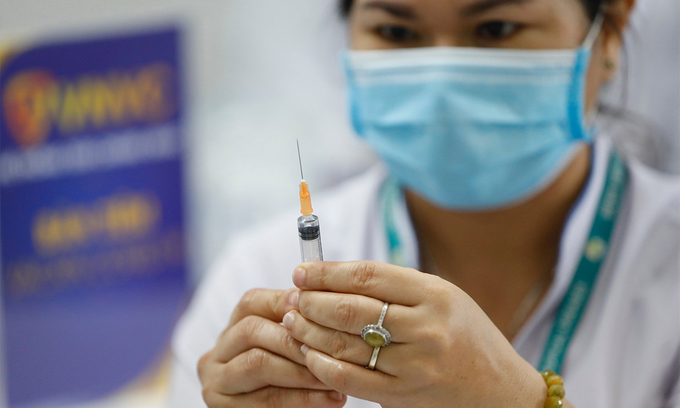 A medical staff prepares to inject Covid-19 vaccine on a person. Photo by VnExpress/Huu Khoa.