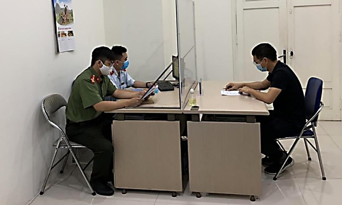 A 39-year-old man (R) in Hanoi is fined for falsely claiming online that the capital was going under lockdown, May 10, 2021. Photo courtesy of the Hanoi Department of Information and Communications.