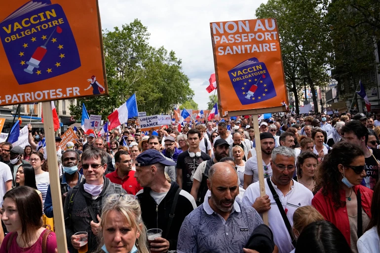 Protesters hold up signs that read 'no to the vaccine passport' during a demonstration in Paris [Michel Euler/AP]