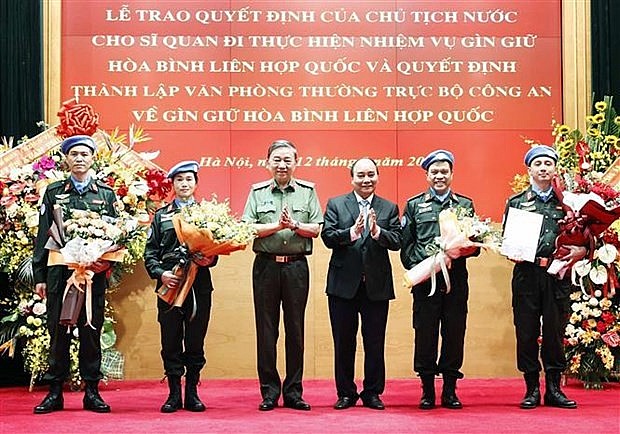 President Nguyen Xuan Phuc (third from right) presents the decision and flowers to new officers assigned to United Nations peacekeeping missions (Photo: VNA)