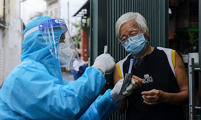 A medic guides a man in HCMC's Binh Thanh District to use a test kit on himself, August 23, 2021. Photo by VnExpress