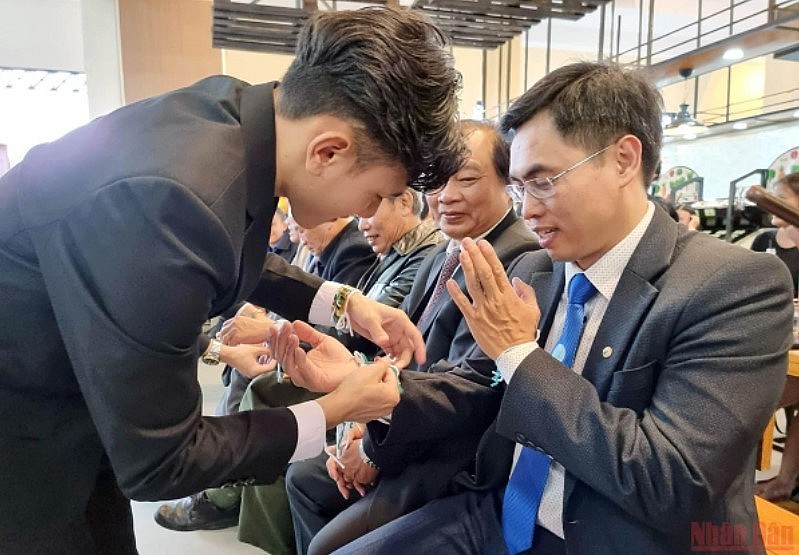 Lao students perform a wrist-tying ceremony for attendees. (Photo: Nhan Dan Newspaper)