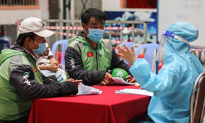 Shippers listen to a health worker at a Covid-19 vaccination point in HCMC's District 11, August 2, 2021. Photo: VnExpress