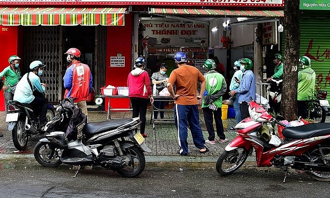 Shippers and customers wait in front of a noodle restaurant in HCMC's District 1 for their take-away orders, September 2021. Photo: VnExpress