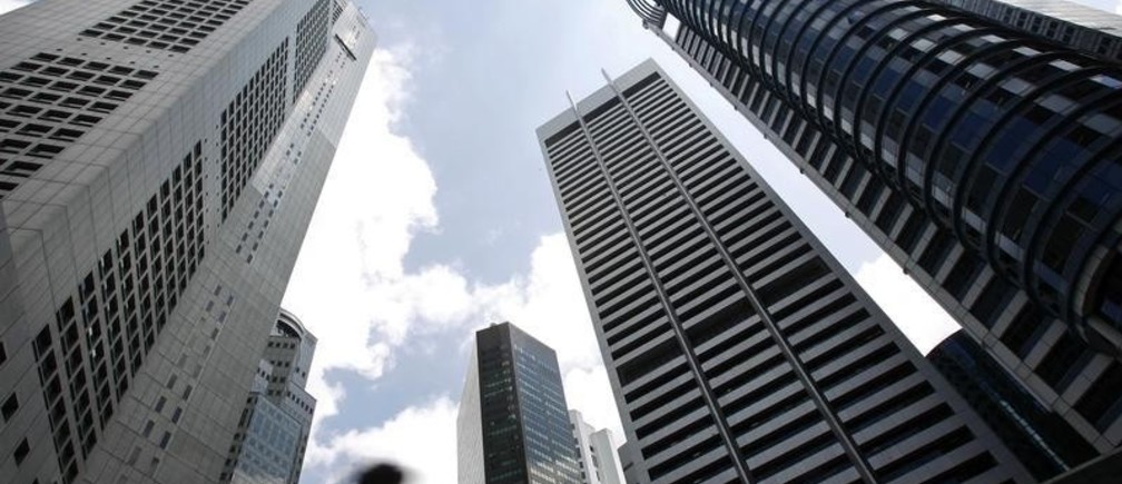 A man walks past buildings at the central business district of Singapore February 14, 2007. Singapore's trade-reliant economy expanded faster than expected in the fourth quarter on a pick up in domestic activity, data showed on Wednesday, prompting the government to lift its expectations for 2007.